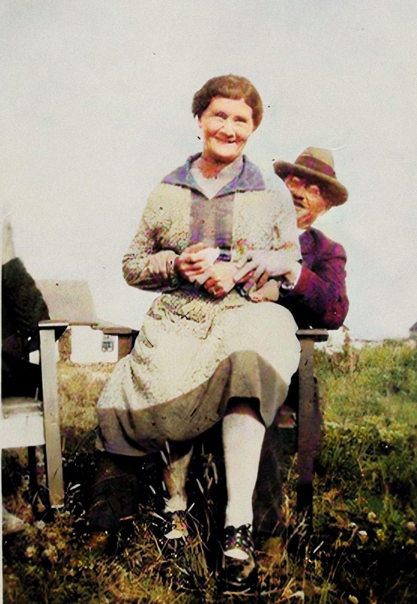 Woman sitting on a gentlemans knee, outside and smiling.