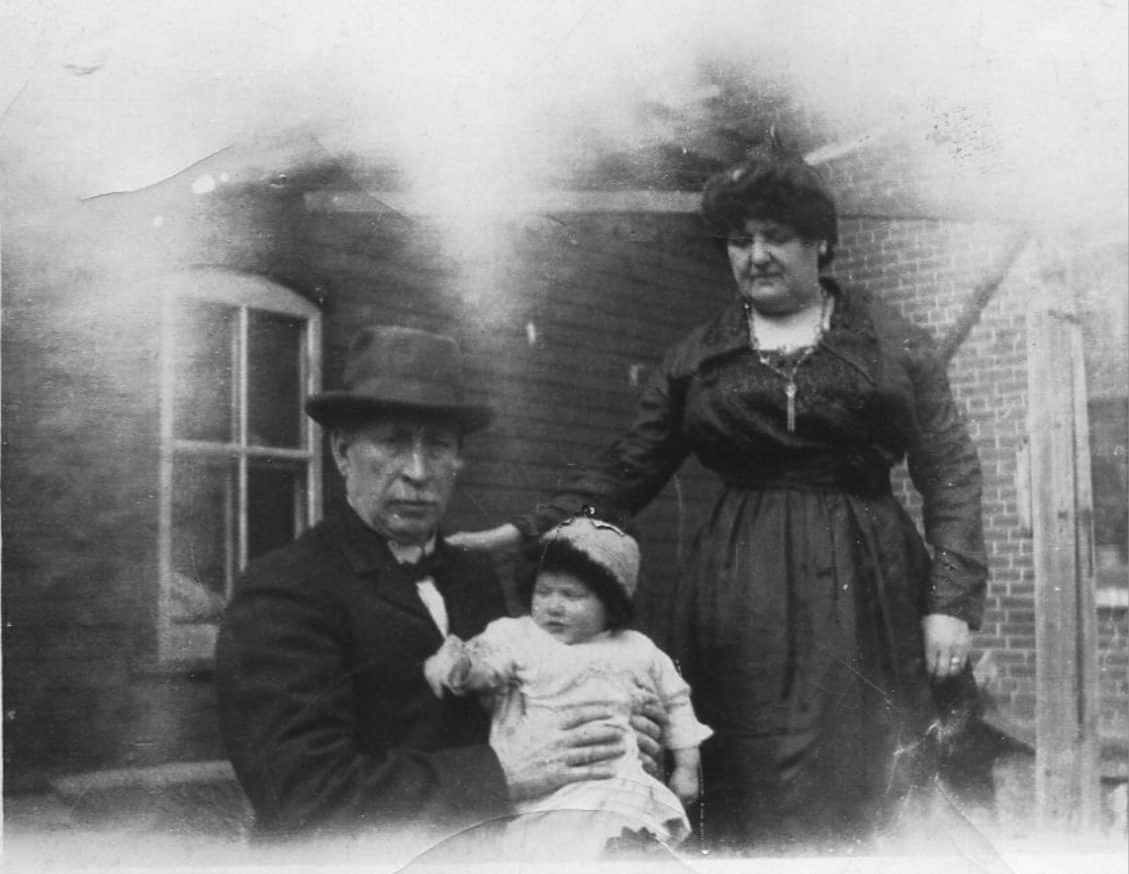 Man and woman posing with a baby.