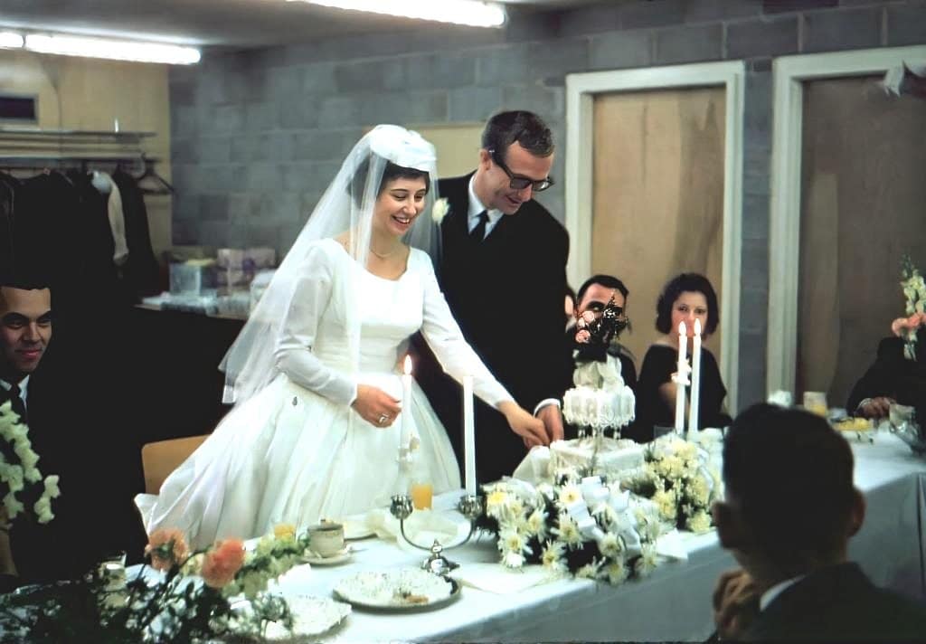 Bride cutting the wedding cake with groom beside her.
