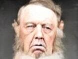 The face of a man with a grey beard and large sideburns.