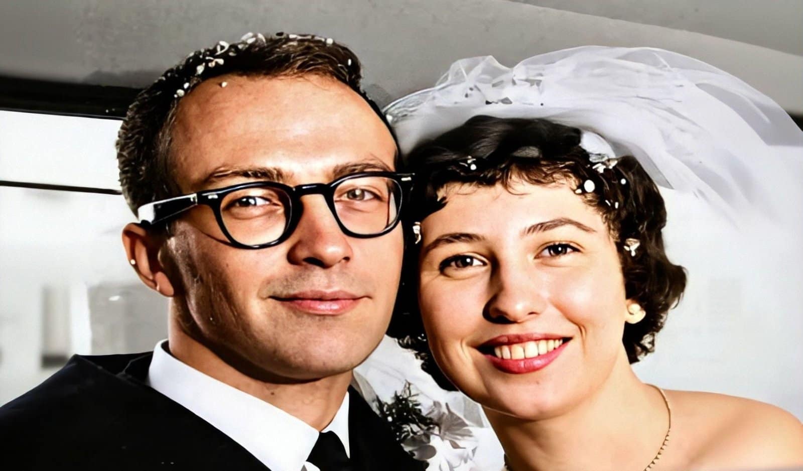 A couple in wedding attire posing in a car window.