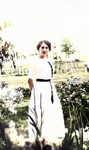 A young lady posing in a field of flowers in a white dress.