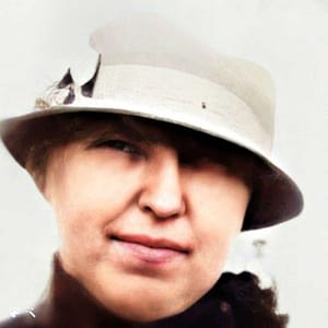 A woman in a light coloured hat and dark coat. head only captured.