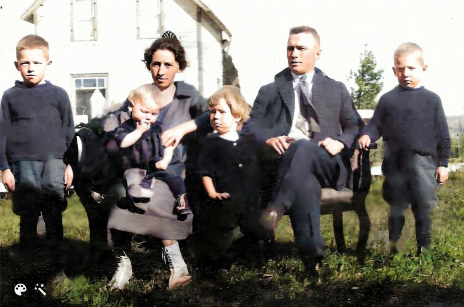 A family of six posing outside sitting on chairs. They are all dressed up.