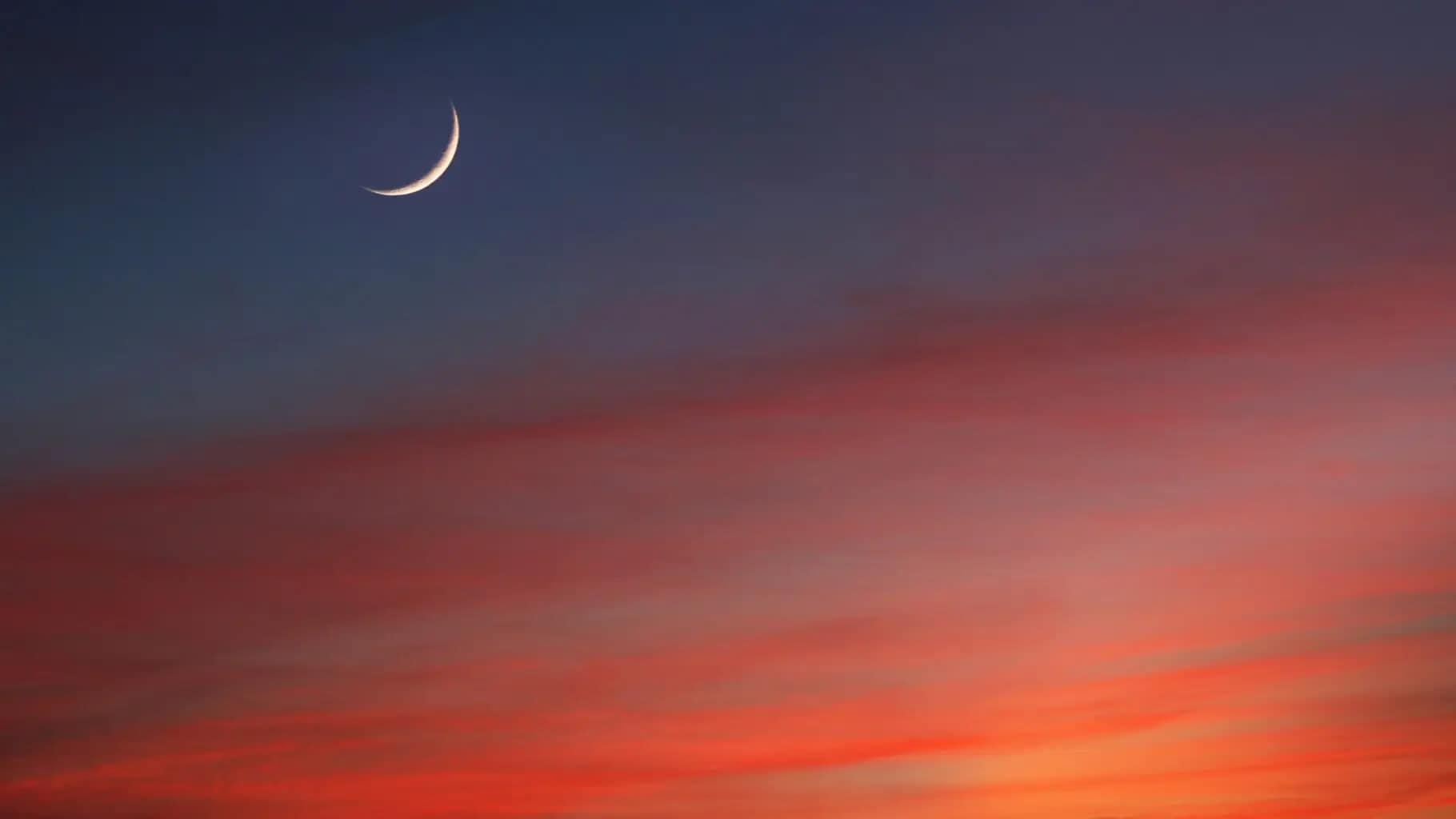 Scenic sky at night with crescent moon in a dark sky with red .