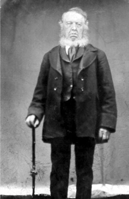 An image of a stately gentleman with a white beard and holding a sheleighly.