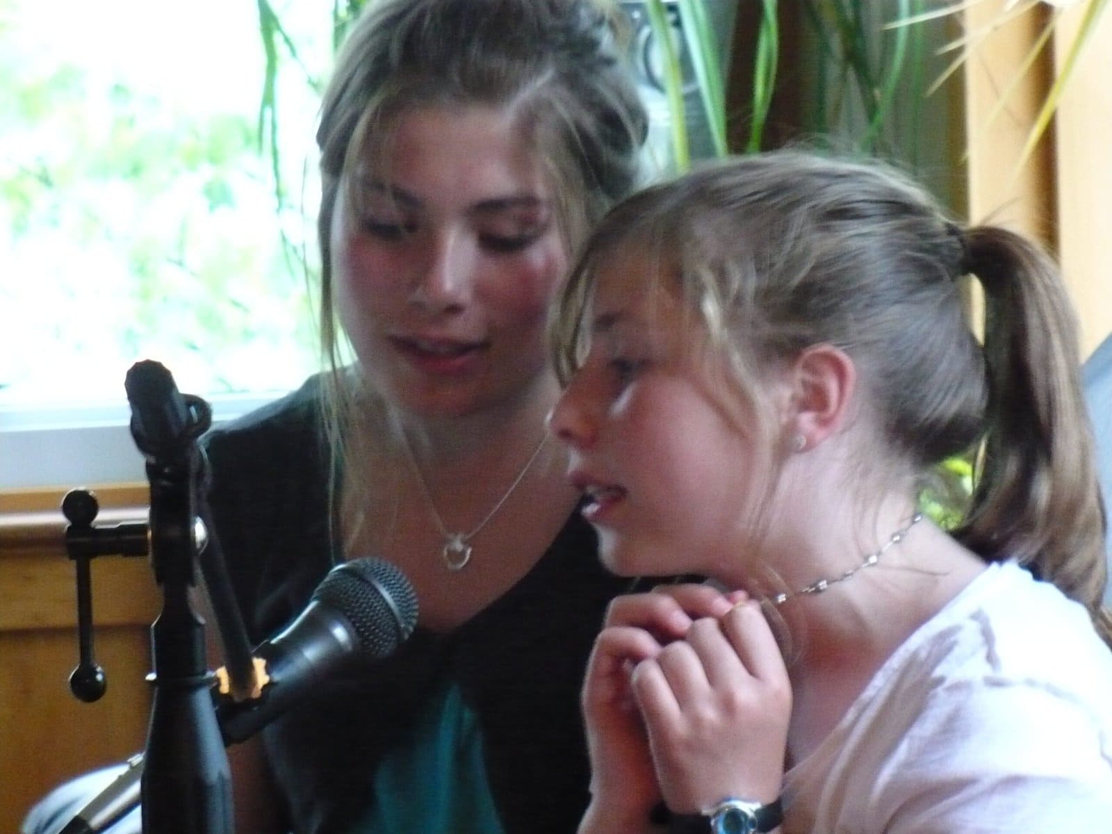 Two young girls singing into a microphone.