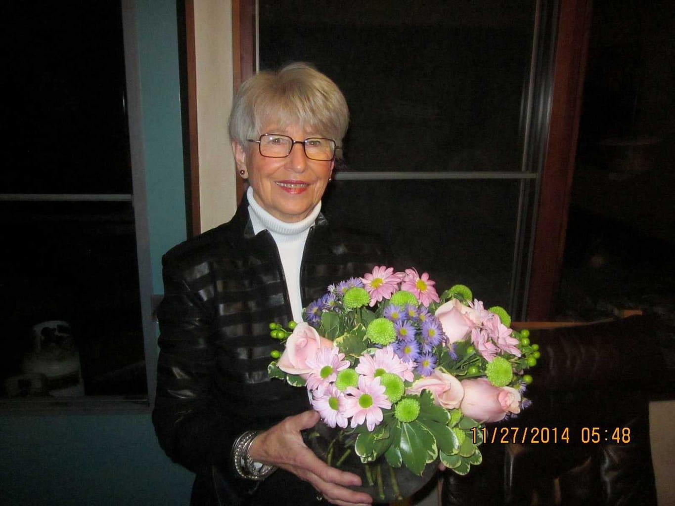 A woman holding a bouquet of colourful flowers.